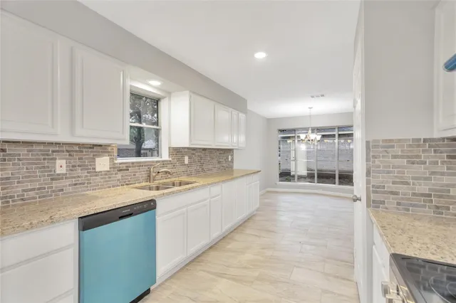a large kitchen with granite countertop a sink and cabinets