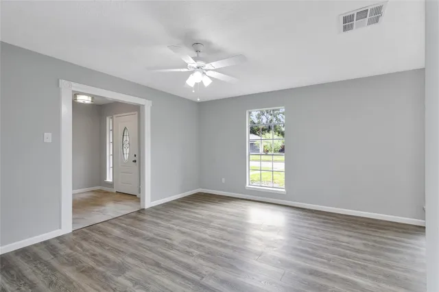 a view of an empty room with wooden floor and a window