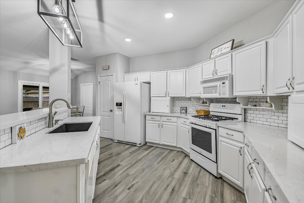 1312 Pigeon View Street Round Rock, TX 78665 - Photo 15 of 30 a kitchen with granite countertop a sink stove and refrigerator