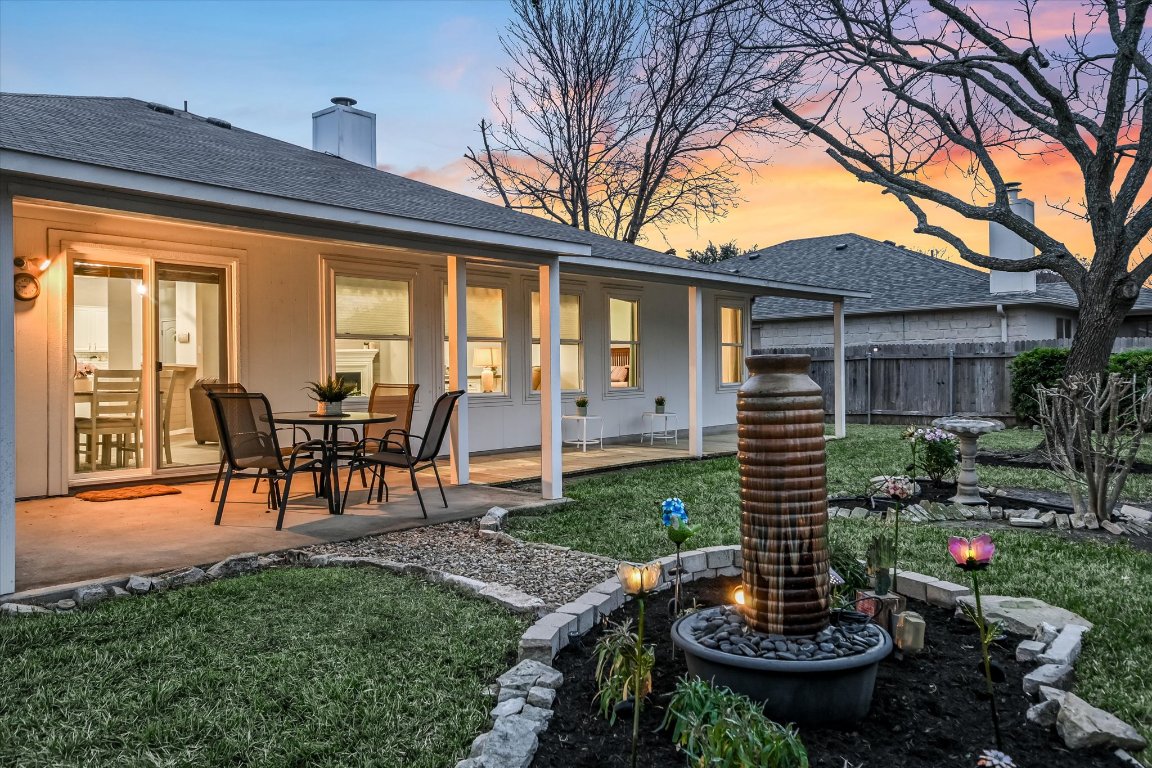 1312 Pigeon View Street Round Rock, TX 78665 - Photo 3 of 30 a view of a backyard with table and chairs potted plants and a large tree