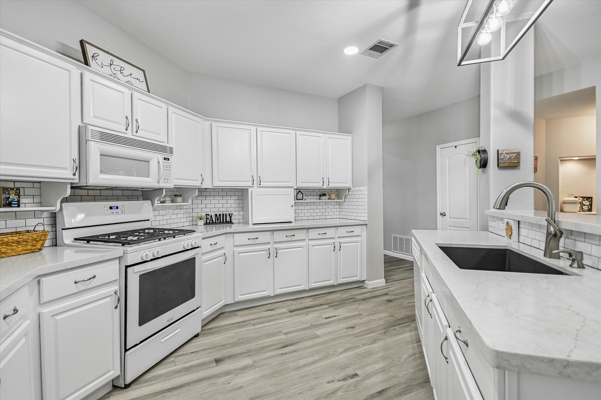 1312 Pigeon View Street Round Rock, TX 78665 - Photo 6 of 30 Kitchen with white appliances, white cabinets, light wood-type flooring, light stone countertops, and recessed lighting