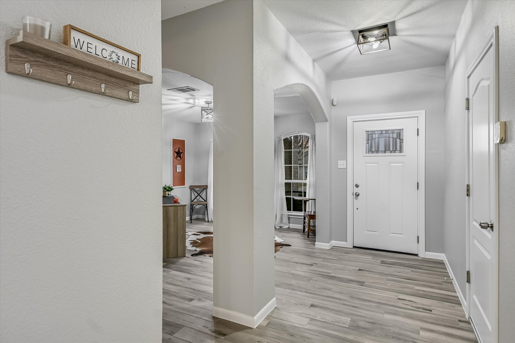 1312 Pigeon View Street Round Rock, TX 78665 - Photo 8 of 30 Entrance foyer with arched walkways, light wood-style flooring, and a textured wall