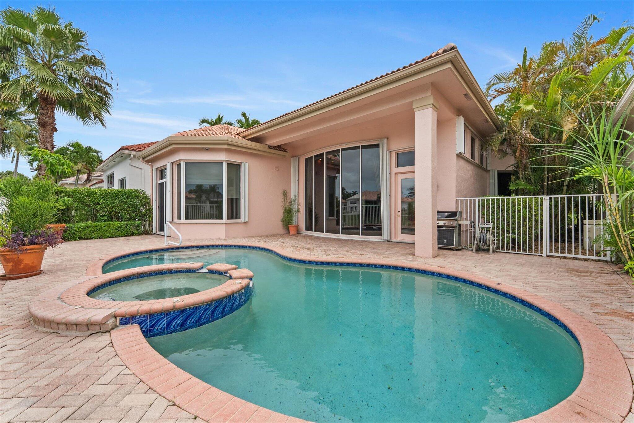7081 Mallorca Crescent Boca Raton, FL 33433 - Photo 18 of 26 a view of a white house with swimming pool lawn chairs and plants