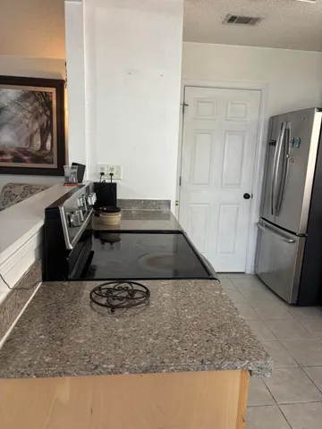 a kitchen with kitchen island a stove a refrigerator and a counter top space