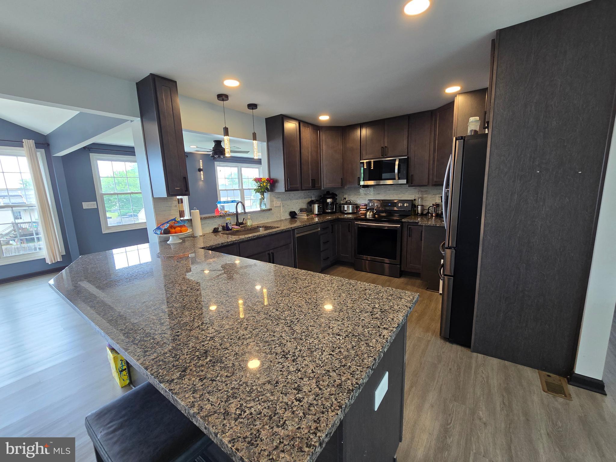 7513 Saffron Court Hanover, MD 21076 - Photo 8 of 42 a kitchen with stainless steel appliances granite countertop a sink a stove and a wooden floors