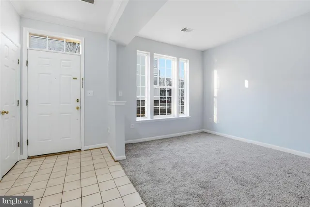 a view of an empty room with window and hardwood floor