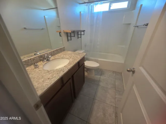 a bathroom with a granite countertop sink a toilet and shower