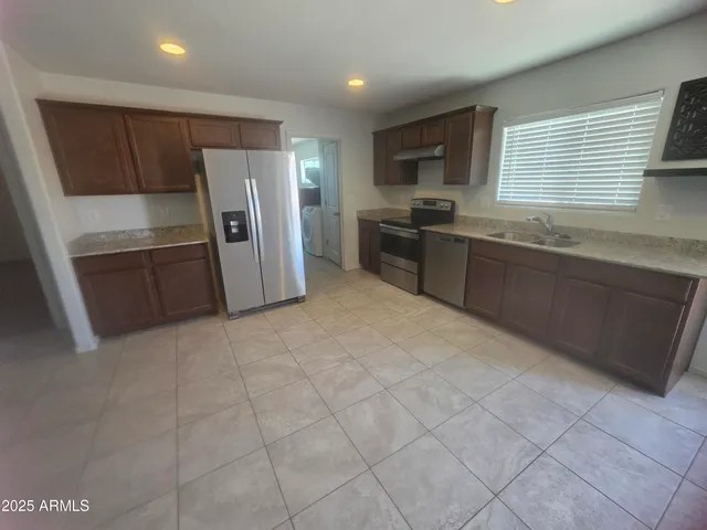 a kitchen with granite countertop a refrigerator and a stove top oven