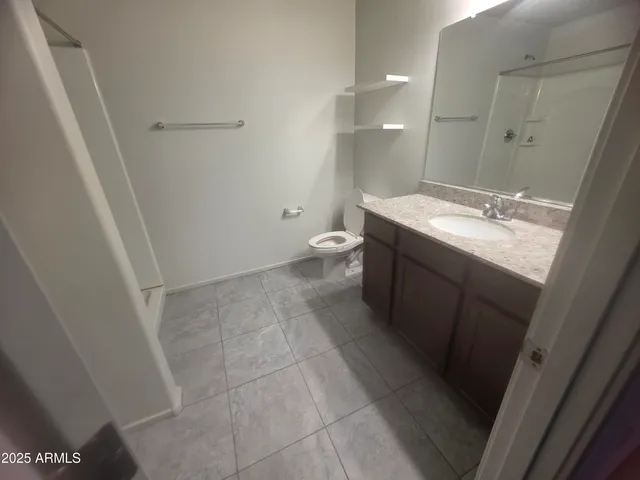a bathroom with a granite countertop sink a toilet and a mirror