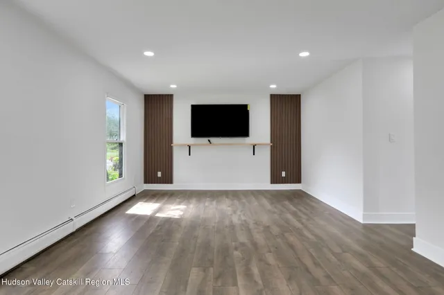 a view of a livingroom with wooden floor and a flat screen tv