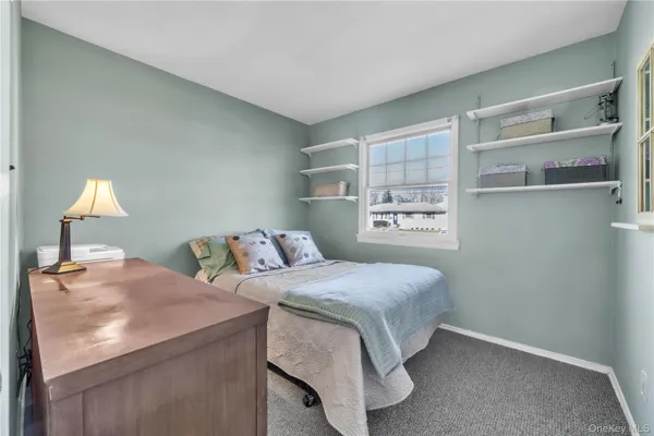 a bedroom with a bed and a lamp on the dresser