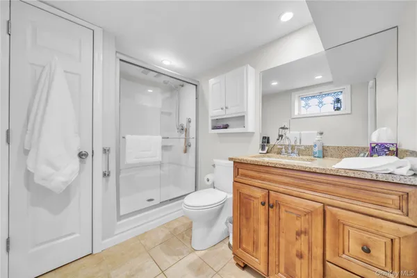 a spacious bathroom with a granite countertop sink a toilet a mirror and shower