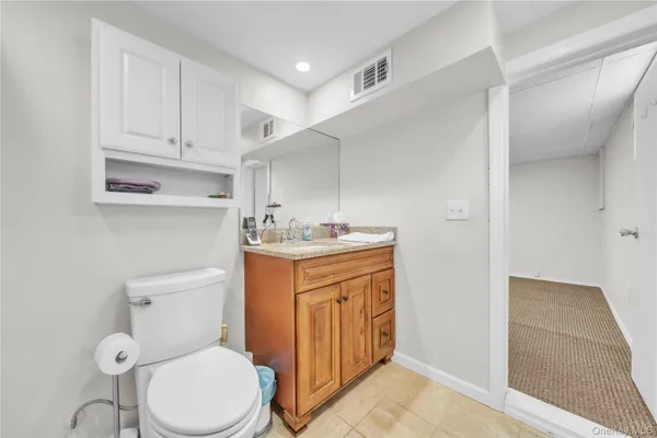 a bathroom with a granite countertop toilet sink and mirror