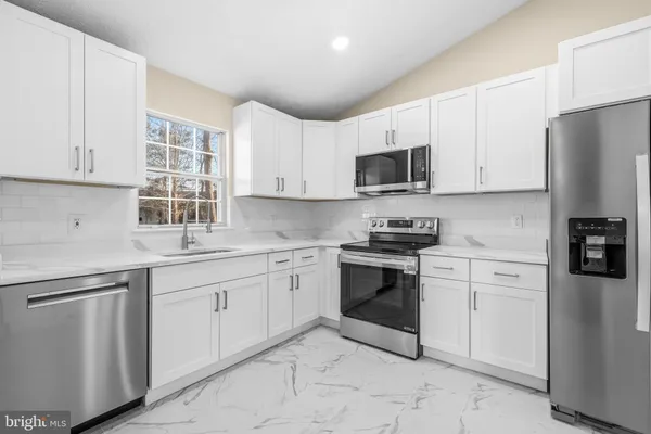 a kitchen with cabinets stainless steel appliances and a window