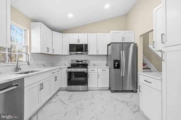 a kitchen with stainless steel appliances granite countertop a refrigerator sink and stove