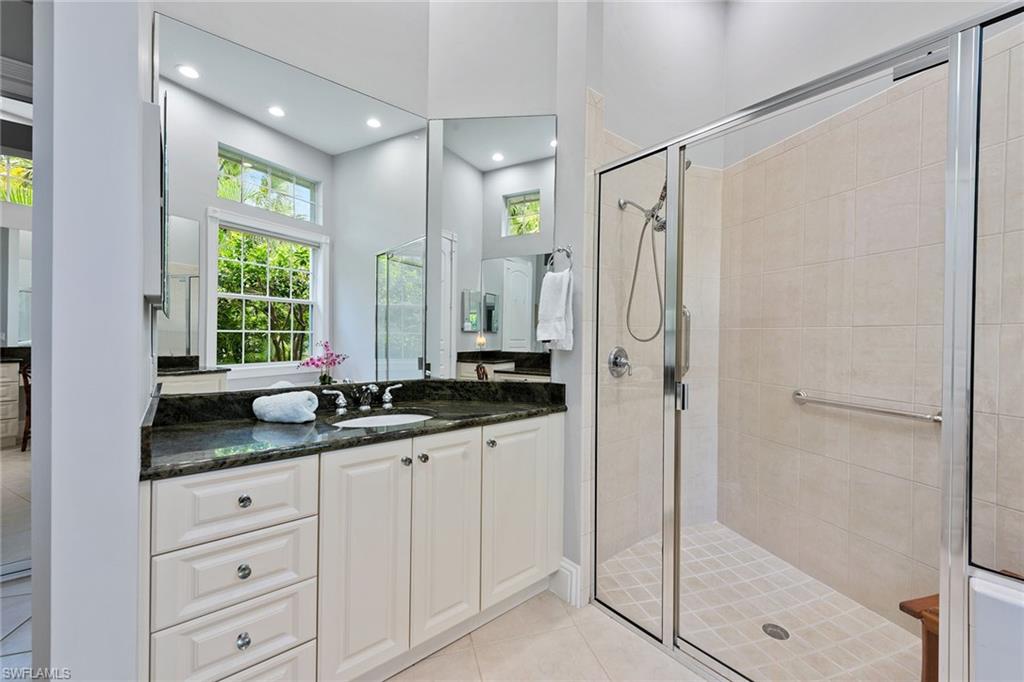 566 Eagle Creek Drive Naples, FL 34113 - Photo 13 of 25 a bathroom with a granite countertop sink a mirror a window and a shower