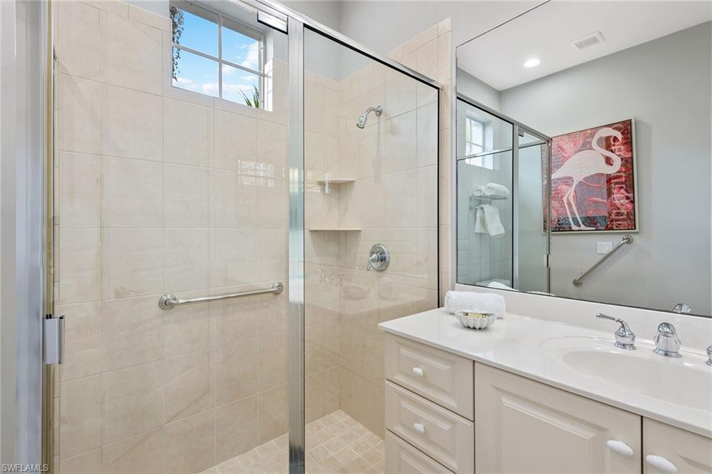 566 Eagle Creek Drive Naples, FL 34113 - Photo 17 of 25 a bathroom with a shower sink vanity and mirror