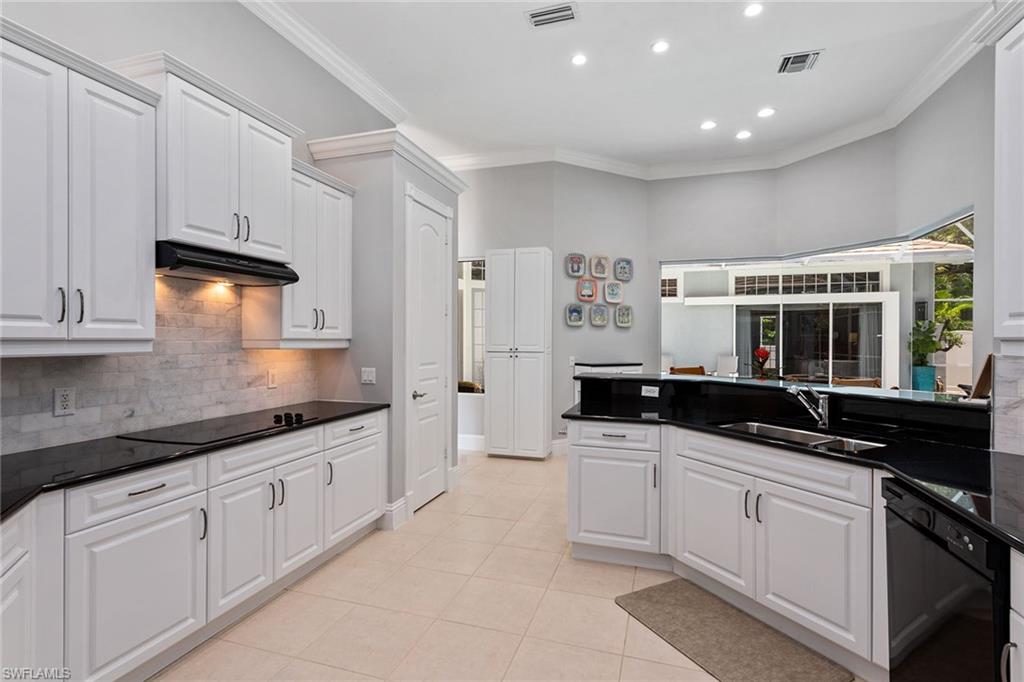 566 Eagle Creek Drive Naples, FL 34113 - Photo 6 of 25 a kitchen with granite countertop a sink and white cabinets