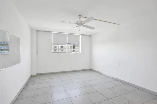 an empty room with windows and ceiling fan