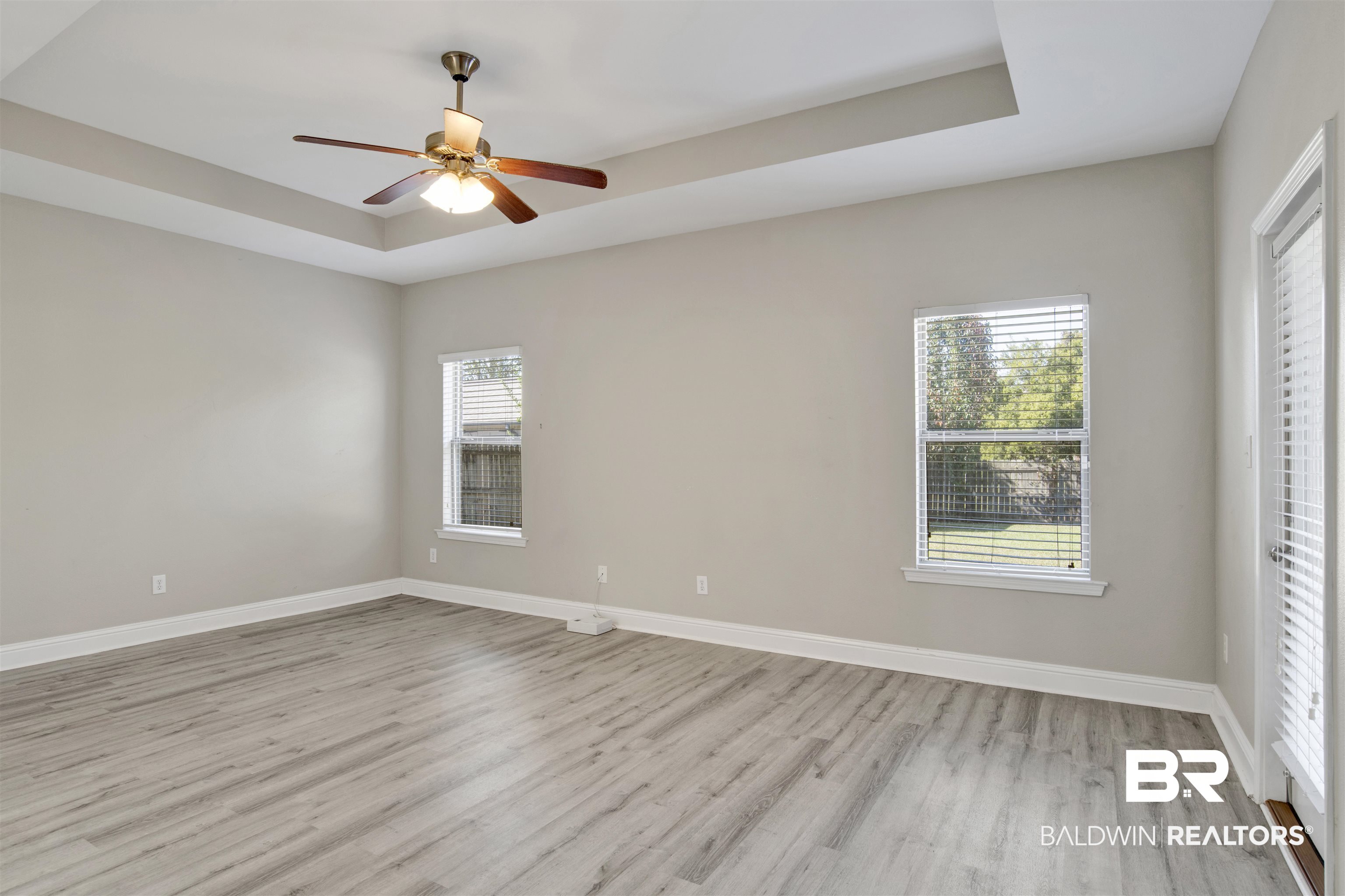 24159 Tullamore Drive Daphne, AL 36526 - Photo 20 of 31 Empty room with a tray ceiling, light wood-type flooring, and ceiling fan