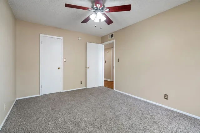 a view of an empty room and chandelier fan