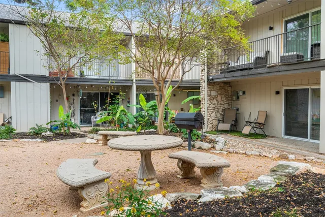 a view of a backyard with table and chairs potted plants and a large tree