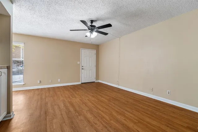 an empty room with wooden floor fan and windows