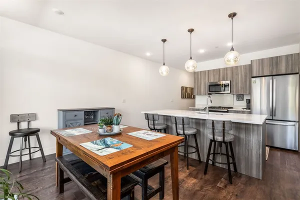 a kitchen with stainless steel appliances granite countertop a stove a refrigerator a kitchen island a dining table and chairs