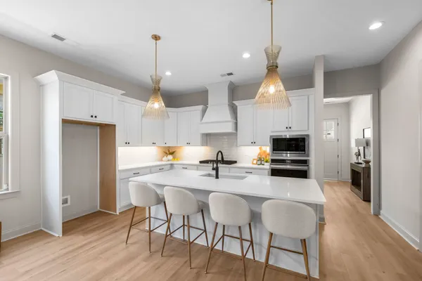 a kitchen with stainless steel appliances kitchen island granite countertop a dining table chairs and a refrigerator