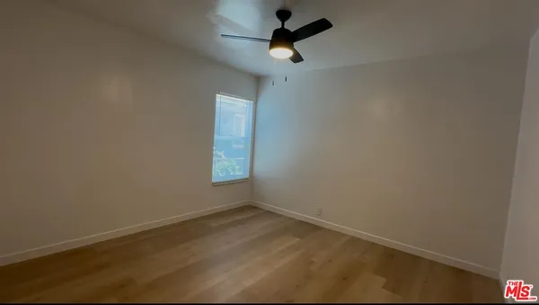 en empty room with ceiling fan and window