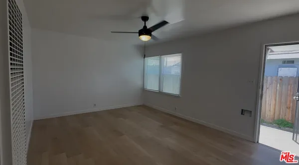 an empty room with ceiling fan and window