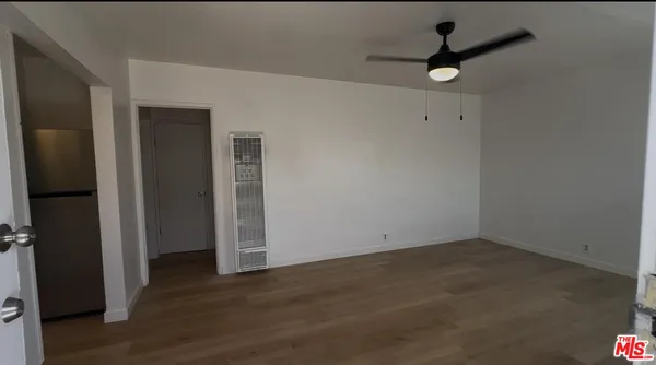 an empty room with wooden floor closet and windows