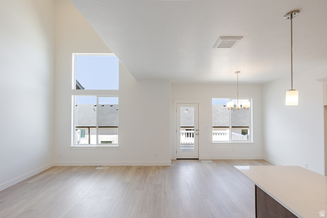 4748 Heartwood Road, Unit 434 Mapleton, UT 84664 - Photo 4 of 18 Unfurnished dining area with a chandelier, light wood finished floors, and a high ceiling