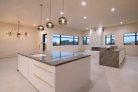 a large kitchen with granite countertop a sink a counter and chairs