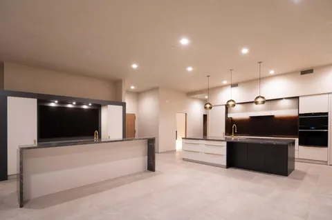 a living room with stainless steel appliances kitchen island a flat screen tv and a couch