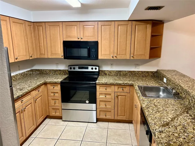 a kitchen with stainless steel appliances granite countertop a stove a sink and a microwave