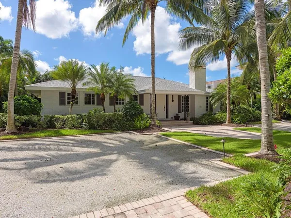 front view of a house with a yard and palm trees
