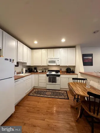 a white kitchen with wooden floor and stainless steel appliances
