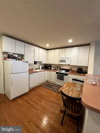 a kitchen with a sink a stove a refrigerator cabinets and a dining table