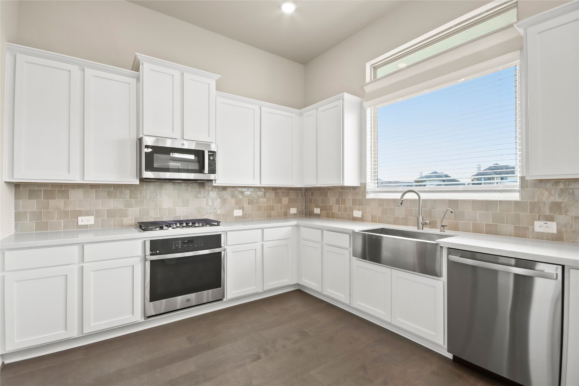 136 Peninsula Point Drive Montgomery, TX 77356 - Photo 7 of 30 a kitchen with stainless steel appliances granite countertop white cabinets a sink and dishwasher a stove with wooden floor