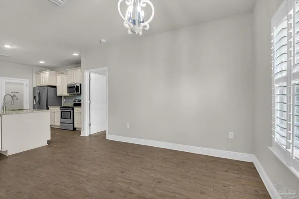 a view of an empty room with kitchen and window