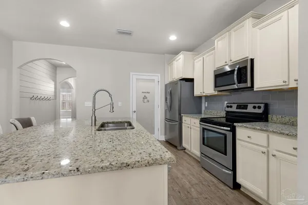 a kitchen with stainless steel appliances granite countertop a sink a stove top oven and refrigerator