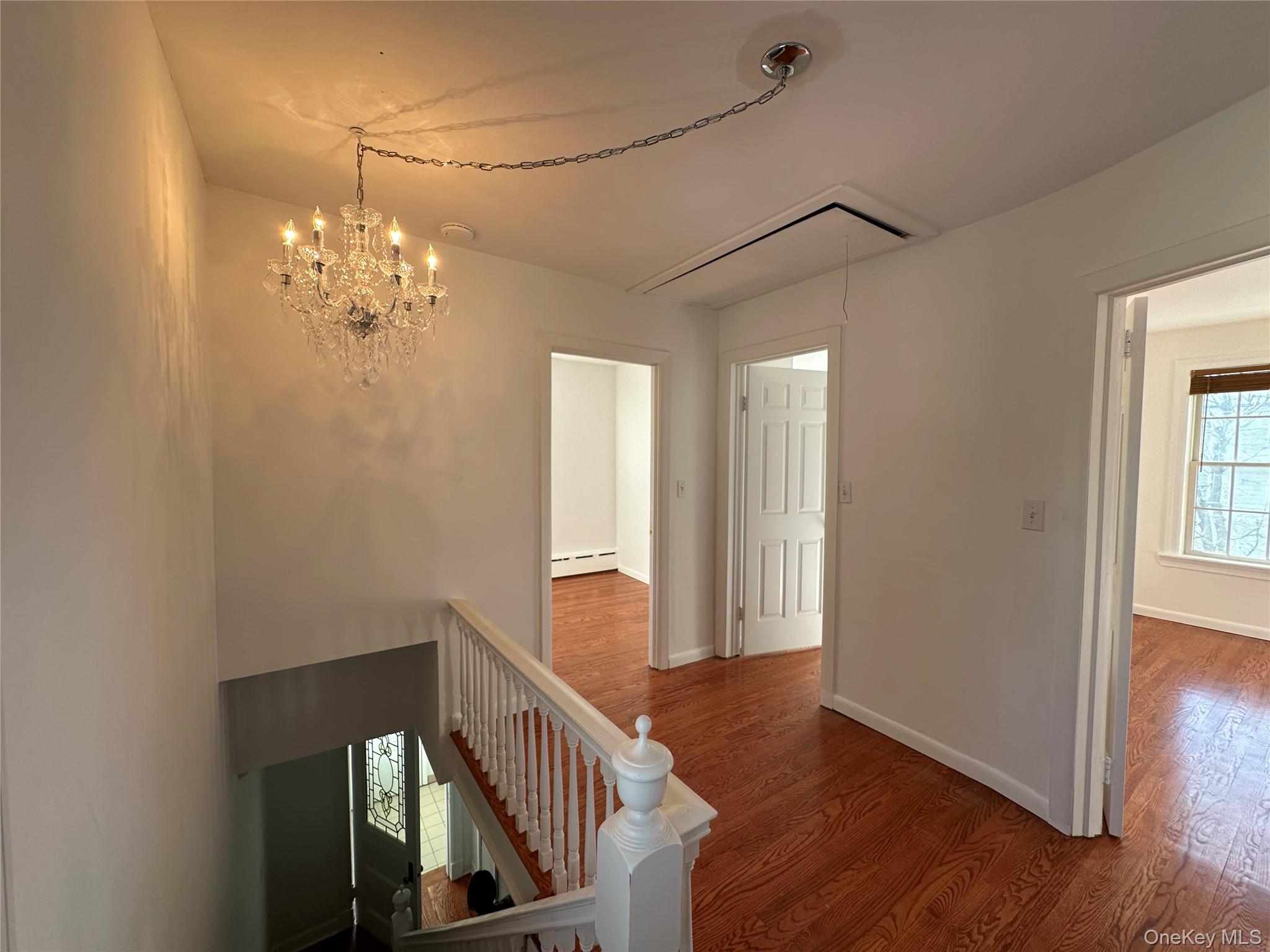 197 Johnson Road Scarsdale, NY 10583 - Photo 18 of 36 Hallway featuring an inviting chandelier, a baseboard radiator, and wood-type flooring