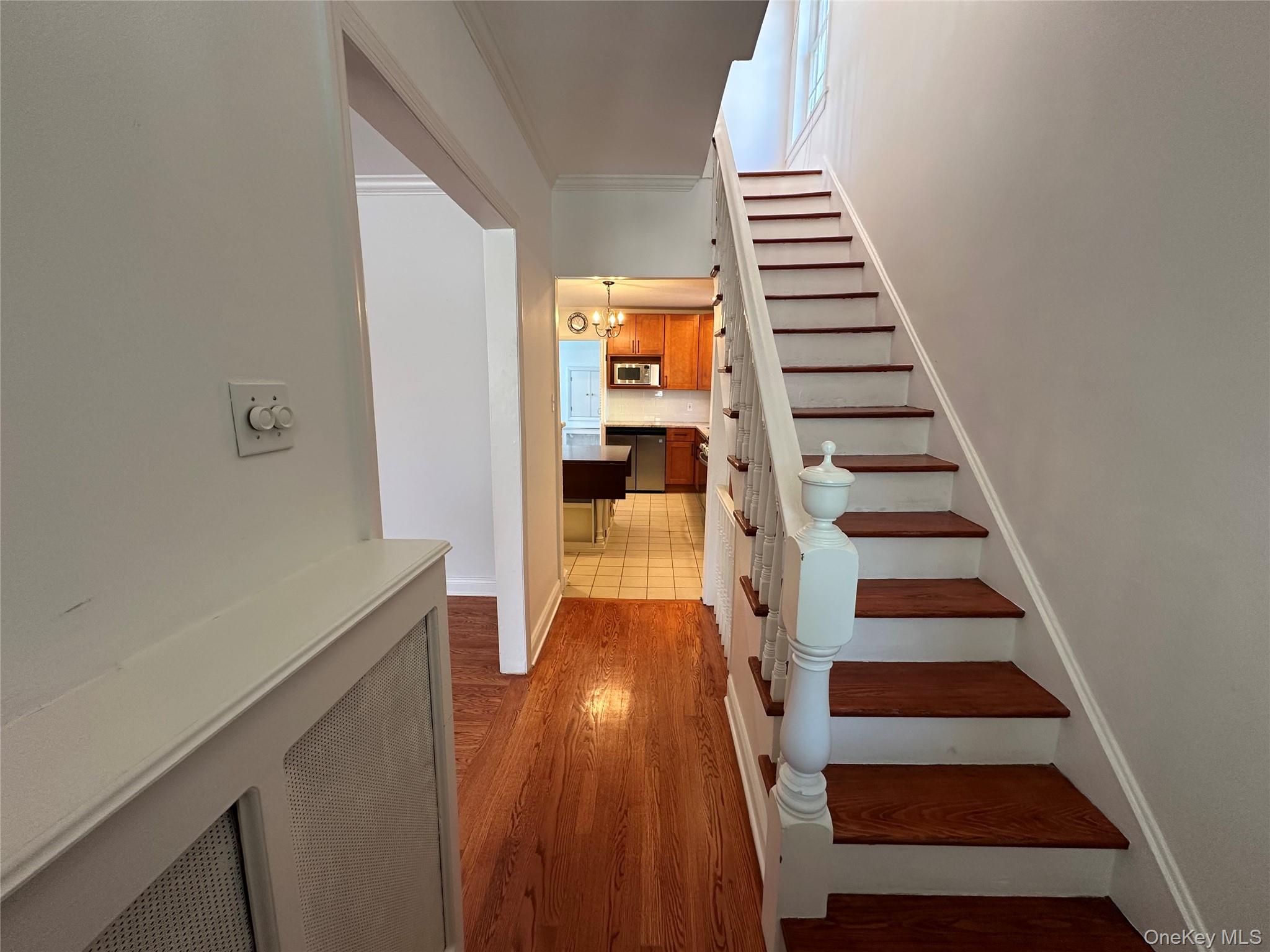 197 Johnson Road Scarsdale, NY 10583 - Photo 20 of 36 Staircase with crown molding, hardwood / wood-style floors, and a notable chandelier