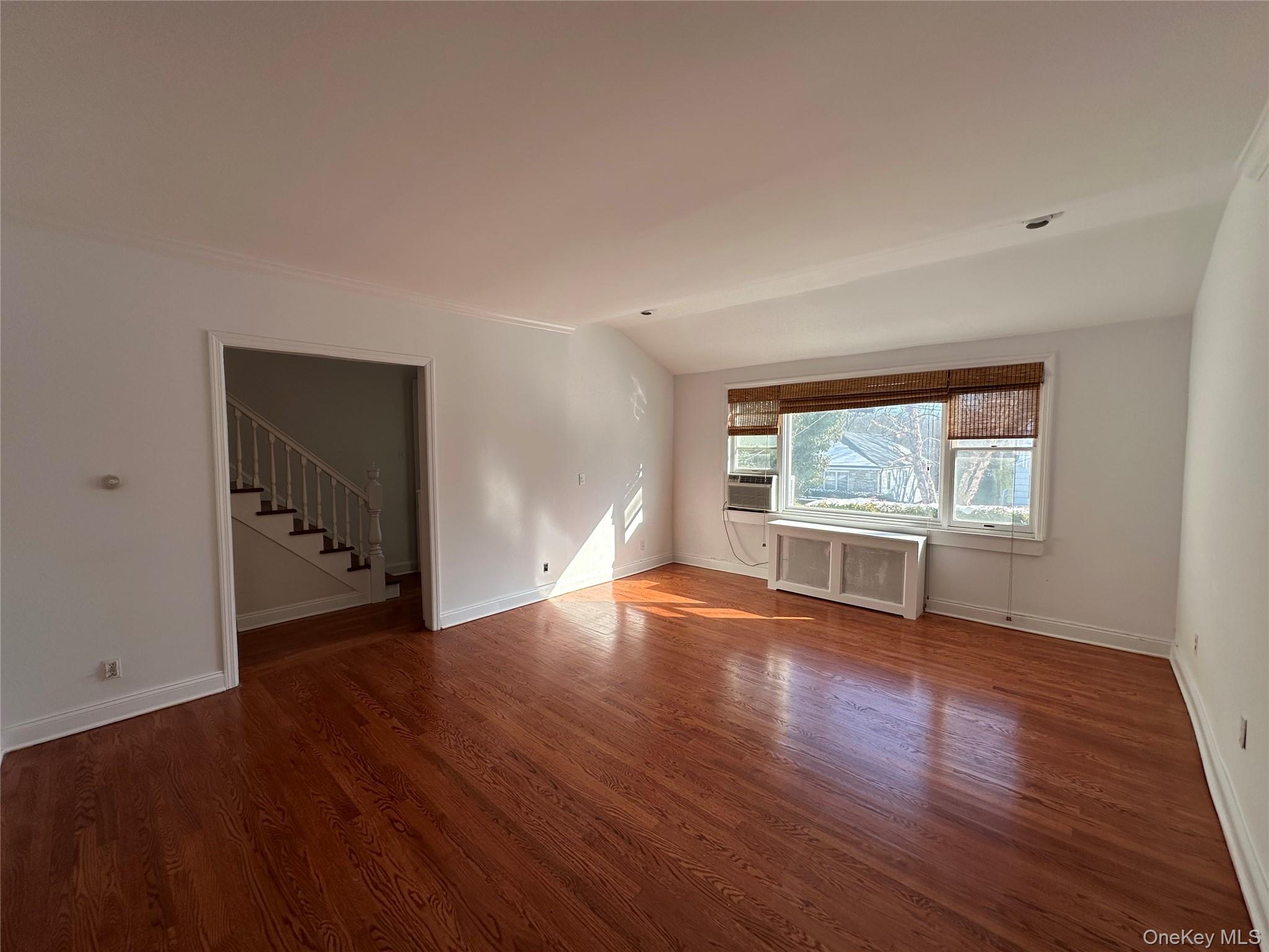 197 Johnson Road Scarsdale, NY 10583 - Photo 28 of 36 Living room facing the street featuring cooling unit, lofted ceiling, wood-type flooring, and radiator
