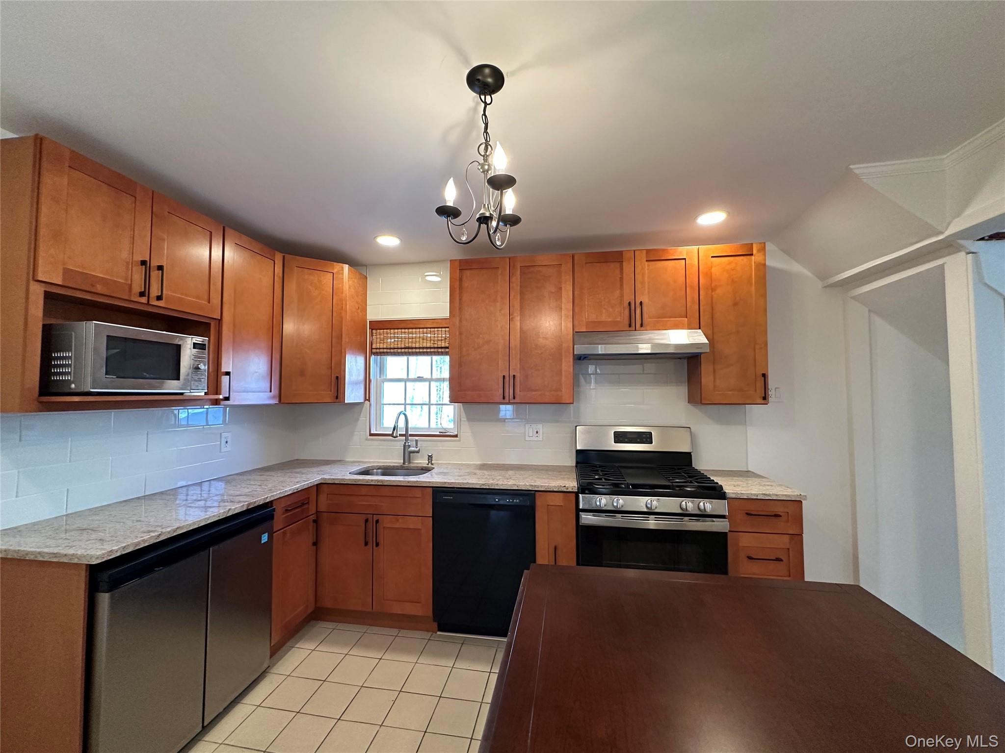 197 Johnson Road Scarsdale, NY 10583 - Photo 3 of 36 Kitchen featuring sink, decorative light fixtures, light tile patterned floors, stainless steel appliances, and decorative backsplash