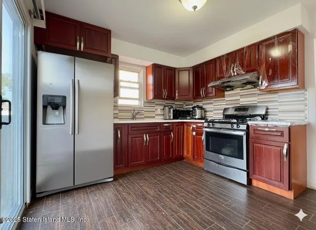 a kitchen with stainless steel appliances granite countertop a stove top oven a refrigerator and dishwasher with wooden floor