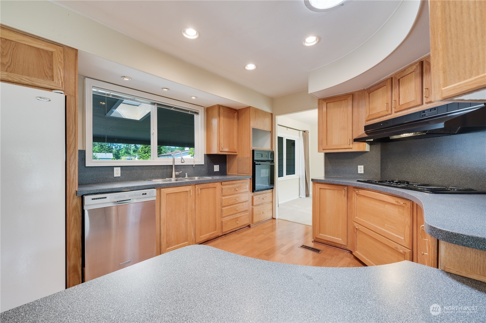 23803 Lake Drive West Bothell, WA 98021 - Photo 12 of 32 a kitchen with stainless steel appliances granite countertop a refrigerator a stove and a sink with wooden floor