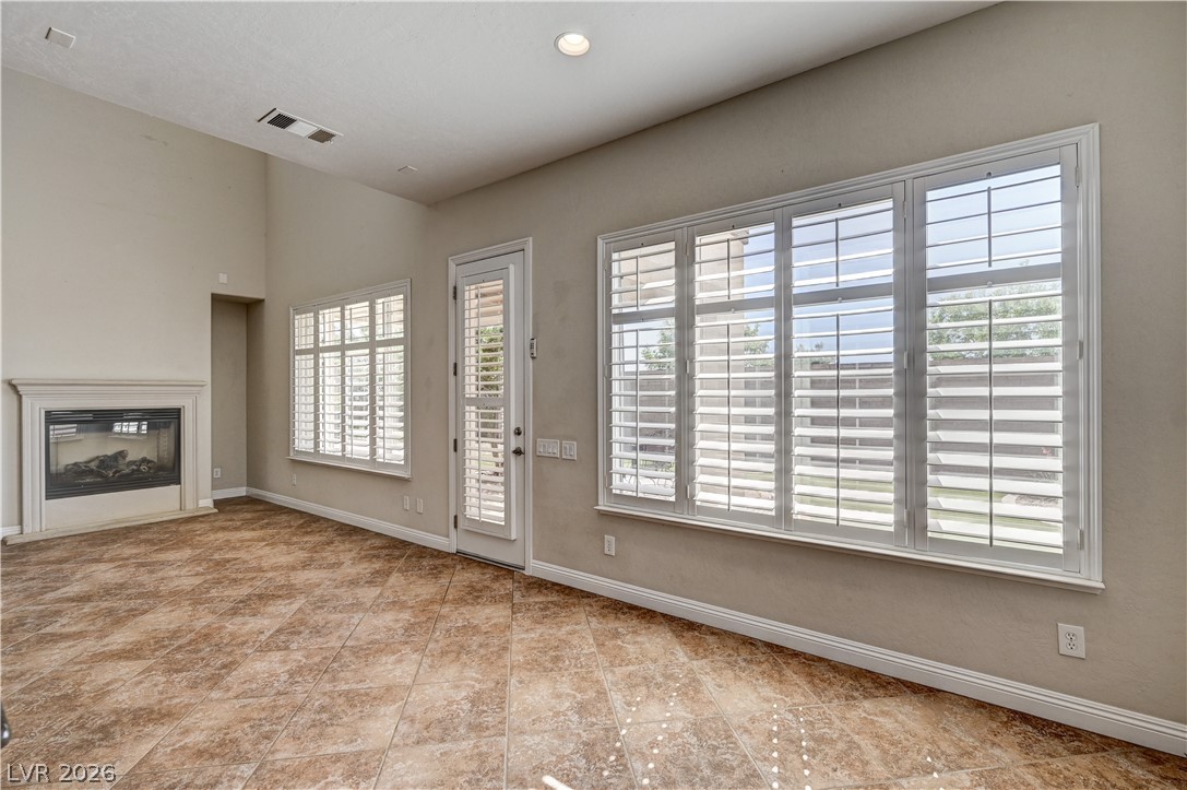 2793 Rosenhearty Drive Henderson, NV 89044 - Photo 20 of 85 This living area features a charming fireplace, vaulted ceilings, and a door leading outside.