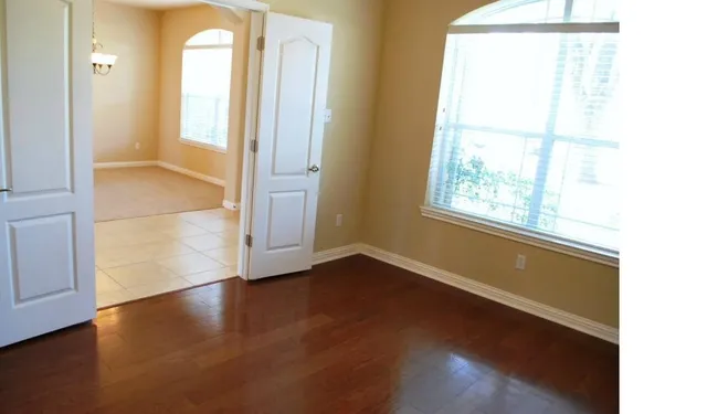 an empty room with wooden floor and windows